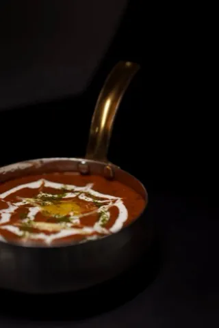 Dal makhani in a brass bowl, finished with a swirl of cream.